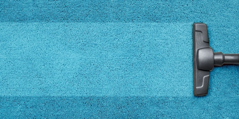 Vacuum cleaning the blue carpet.